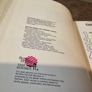 May include: A white book with a red and white gingham pattern on the cover. The book title is "Better Homes and Gardens Test Kitchen". The book cover also includes the text "Our seal assures you that every recipe in All-Time Favorite Recipes is endorsed by the Better Homes and Gardens Test Kitchen. Each recipe is carefully tested for family appeal, practicality, and deliciousness."