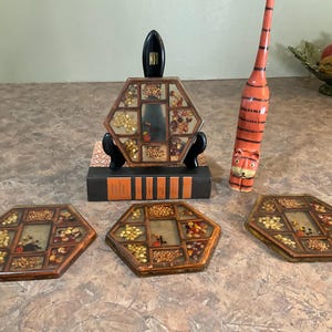 Pode incluir: Uma coleção de itens decorativos, incluindo três bandejas hexagonais com várias sementes e grãos, uma estatueta de tigre laranja alta e uma peça central de exibição. As bandejas e a exibição têm uma moldura de madeira. A estatueta do tigre tem cerca de 30 cm de altura.