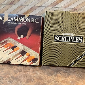 May include: Two vintage board games: "Backgammon B.C." with dice and game pieces on a red background, and "A Question of Scruples" in a black and gold checkered box. The backgammon box has the text "The authentic game classic."