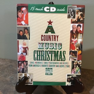 May include: A book titled "A Country Music Christmas" with a red and green Christmas tree design on the cover. The book features photos of country music stars and includes a 15-track CD inside. The book is by Edie Hand & Buddy Killen.