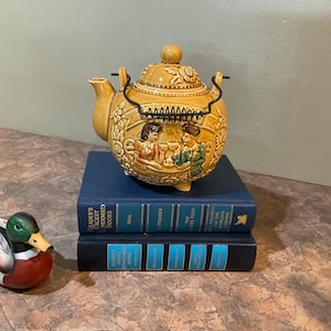 Gyllene honungs-"Tea Time"-tekanna, keramik, med ett par som dricker te och ett fruktmotiv, japanskt märke, trådhandtag