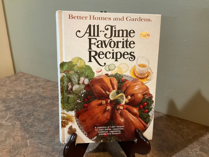 May include: A vintage cookbook titled "All-Time Favorite Recipes" by Better Homes and Gardens. The cover features a photo of roasted chickens on a silver platter with a green salad and a glass pitcher.