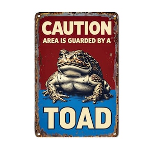 Peut inclure: Panneau métallique rectangulaire à finition vieillie. Le texte « CAUTION AREA IS GUARDED BY A TOAD » est en blanc et jaune. Une illustration détaillée d'un crapaud est centrée sur le panneau, avec un fond rouge et bleu.