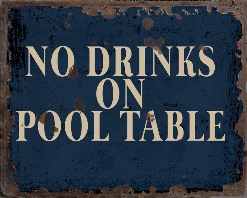 May include: A blue metal sign with white text that reads "NO DRINKS ON POOL TABLE". The sign has a distressed, rusty look.