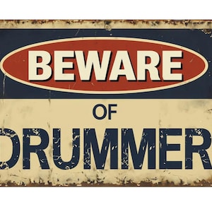 May include: A vintage-style metal sign with a distressed, rusty look. It features a red oval with the word "BEWARE" in white letters, and the words "OF DRUMMER" in blue letters on a cream background.