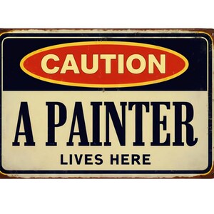 May include: A rectangular metal sign with a distressed finish. The sign features the word "CAUTION" in white on a red oval, above the text "A PAINTER LIVES HERE" in black, on a cream background.
