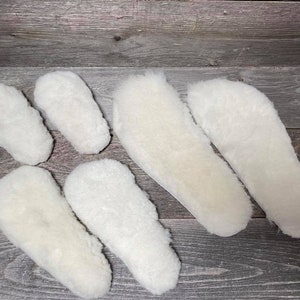 May include: Five white sheepskin insoles of varying sizes. The insoles are made of soft, fluffy sheepskin and are designed to provide comfort and warmth.