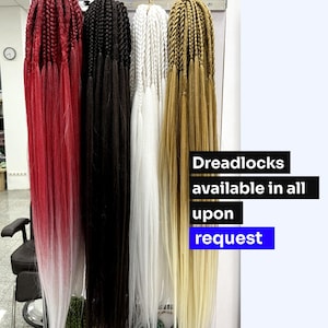 Puede incluir: Cuatro juegos de rastas largas sintéticas colgando de un estante. Las rastas son rojas, negras, blancas y rubias. El texto "Dreadlocks disponibles en todo a pedido" es visible en la imagen.