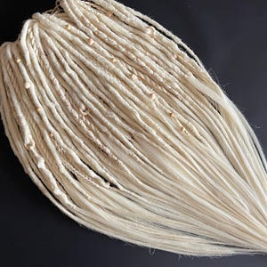 Blonde dreadlocks-extensies met verschillende texturen. Lichte dreadlocks met een vrij uiteinde. Dreadlocks, vlechten en vlechten. Boho blond vlechten