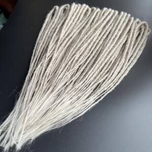 Verlenging van lichtgrijze dreads. Synthetische asgrijze dreads met dubbele en enkele punten. Gehaakte klassieke lichte dreads. Dreads grijsblond