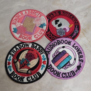 Puede incluir: Cuatro parches bordados circulares con diseños temáticos de libros. Uno dice Kindle Addicts Book Club con una tableta y rosas. Otro dice Dark Romance Book Club con una calavera. Un tercero dice Shadow Daddy Book Club con una rosa y un libro. El último dice Audiobook Lovers Book Club con auriculares y libros.