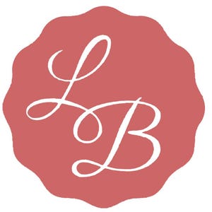 May include: A logo featuring the white cursive letters "L" and "B" on a scalloped, dusty rose-colored background. The letters are intertwined in a flowing, elegant script.