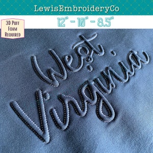 May include: Embroidered design of "West Virginia" in a cursive font, stitched in black thread on a dark blue fabric. The design requires 3D puff foam for a raised effect. The design is available in three sizes: 12 inches, 10 inches, and 8.5 inches.