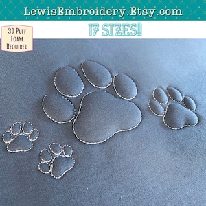 May include: Four embroidered paw prints on a dark blue fabric. The largest paw print is in the centre of the image. The text "17 SIZES!" is at the top of the image. The text "3D Puff Foam Required" is in the top left corner of the image.