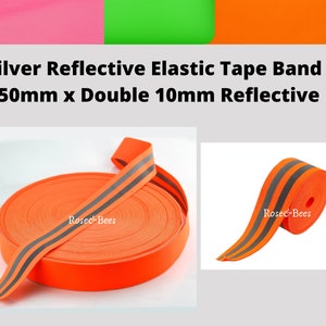 Peut inclure: Un rouleau de ruban &eacute;lastique orange de 50 mm de large avec deux bandes r&eacute;fl&eacute;chissantes argent&eacute;es de 10 mm de large. Le ruban est enroul&eacute; et les bandes r&eacute;fl&eacute;chissantes sont visibles sur l'ext&eacute;rieur du rouleau.