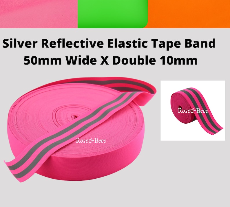 Peut inclure: Bande &eacute;lastique rose avec deux bandes r&eacute;fl&eacute;chissantes argent&eacute;es. La bande mesure 50 mm de large et les bandes r&eacute;fl&eacute;chissantes 10 mm de large. La bande est enroul&eacute;e et la marque "Rosec&Bees" est visible sur la bande.