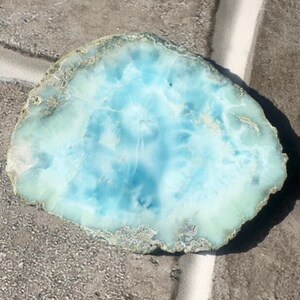 May include: A light blue and green, irregularly shaped, polished stone with a swirling pattern. The stone is a natural crystal.