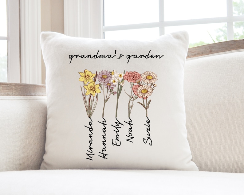 May include: Cream-colored square throw pillow with the text "grandma's garden" in black script. Below the text are illustrations of colorful flowers with names: Miranda, Hannah, Emily, Noah, and Suzle.