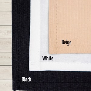 May include: Close-up of three fabric swatches in black, white, and beige. The word "Black" is printed on the black swatch, "White" on the white swatch, and "Beige" on the beige swatch. The fabrics appear to be canvas or a similar material.