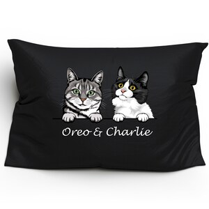 May include: Black pillow with a white background featuring two cats peeking over the top. The cats are a tabby and a black and white cat. The text "Oreo & Charlie" is printed below the cats.