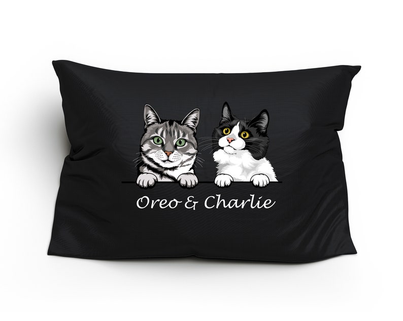 May include: Black pillow with a white background featuring two cats peeking over the top. The cats are a tabby and a black and white cat. The text "Oreo & Charlie" is printed below the cats.
