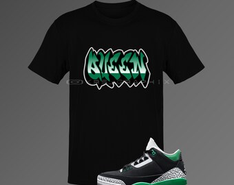 May include: Black t-shirt with the word "NIGERIA" in green and white graffiti-style lettering. A black, green, and white sneaker with a gray patterned design is next to the shirt. The sneaker has a white sole.