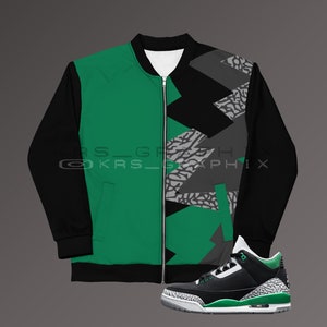 Puede incluir: Una chaqueta bomber negra y verde con un patrón geométrico y una cremallera. Un par de zapatillas negras y verdes con suela blanca.