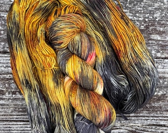 May include: Two skeins of yarn, one black and gray with yellow and orange accents, and one yellow and orange with black and gray accents.