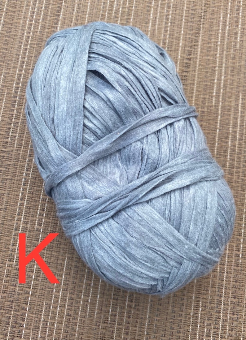 Puede incluir: Un ovillo de hilo gris hecho de camisetas recicladas. El hilo es grueso y texturizado, perfecto para tejer o hacer crochet.
