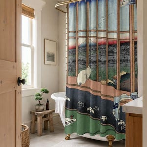 May include: A shower curtain featuring a Japanese woodblock print style illustration of a white cat looking out a window at a landscape with a mountain, blue sky, and green fields. The curtain has a gold-toned rod and rings at the top.