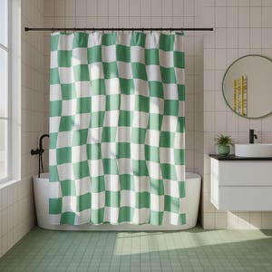 May include: A green and white checkered shower curtain hangs in a bathroom. The curtain is the focal point, with a repeating pattern of large squares. The bathroom has a white bathtub, a round mirror, and a green tiled floor.