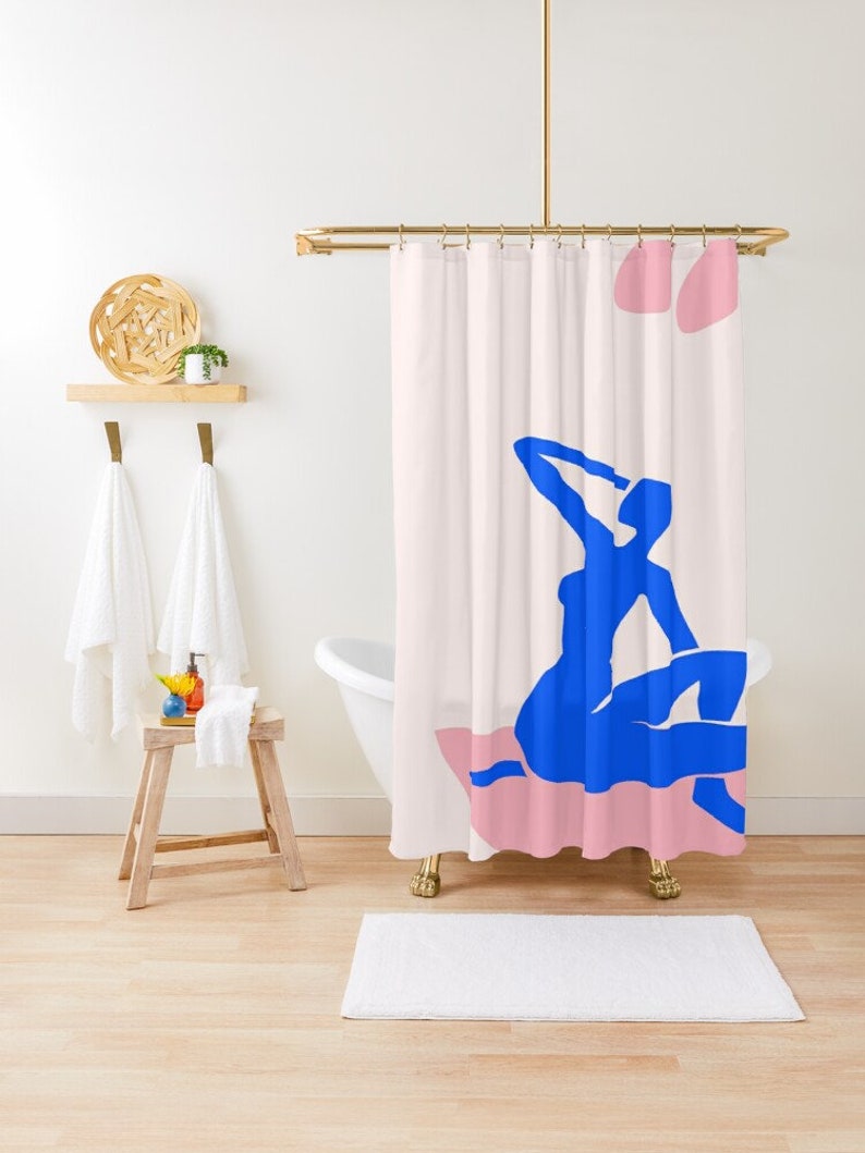 May include: A shower curtain with a pink and white background featuring a blue silhouette of a person sitting on a pink cushion.