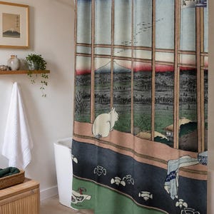 May include: A shower curtain featuring a Japanese woodblock print style illustration of a white cat sitting on a wooden ledge looking out a window at a landscape with a mountain, birds, and trees, with Japanese text in the upper right corner.