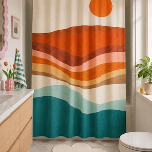 May include: A shower curtain featuring a landscape print with a large orange sun above layered horizontal bands of rust, terracotta, peach, tan, and teal colors. The curtain hangs from a white rod with rings and covers a bathtub area.