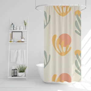May include: A white shower curtain with a pattern of abstract shapes in shades of yellow, orange, and green. The shapes resemble stylized coral or seaweed.