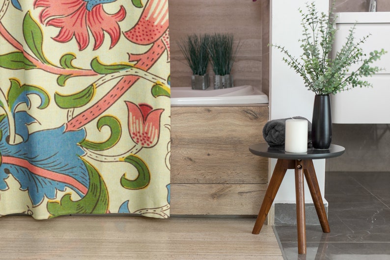 May include: A floral shower curtain with a cream background and a repeating pattern of pink, blue, and green flowers and vines. The curtain is partially open, revealing a white bath and a wooden floor.