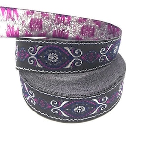May include: Black and silver trim ribbon with a purple and blue floral design. The ribbon is rolled up and the design is visible on both sides.