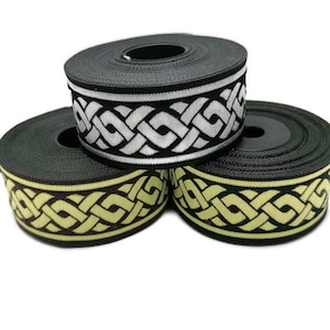 May include: Three spools of black ribbon with a white and yellow woven design. The ribbon has a Celtic knot pattern.