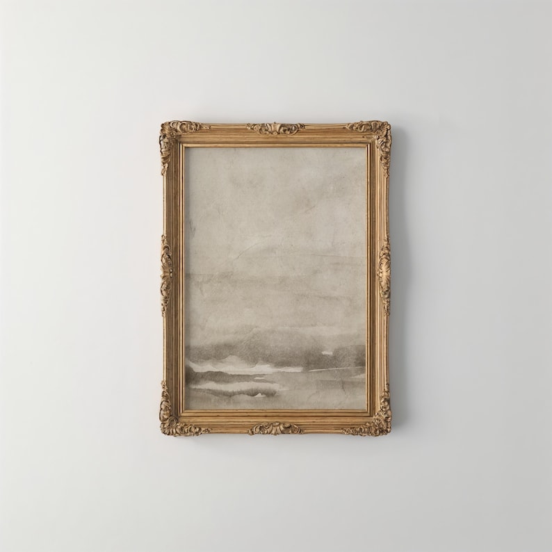 May include: A framed artwork with a gold ornate frame. The artwork features a watercolor-style landscape in shades of gray and beige. The frame has detailed carvings and adds a vintage aesthetic to the piece.