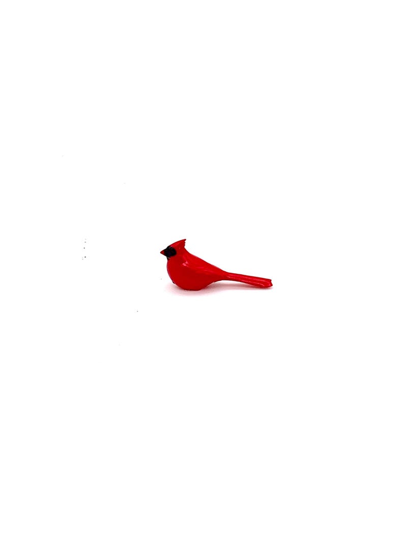 Puede incluir: Una peque&ntilde;a figurita de cardenal rojo con ojos negros. La figurita est&aacute; hecha de pl&aacute;stico y tiene un dise&ntilde;o simple.