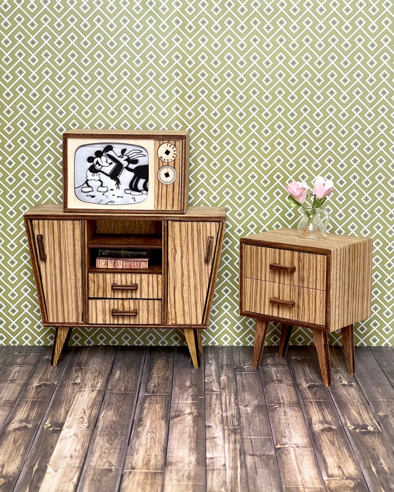 May include: Miniature mid-century modern style furniture set. The set includes a TV with a cartoon image, a cabinet with drawers and doors, and a nightstand with two drawers. The furniture is made of wood with a striped pattern and is set against a patterned green background.
