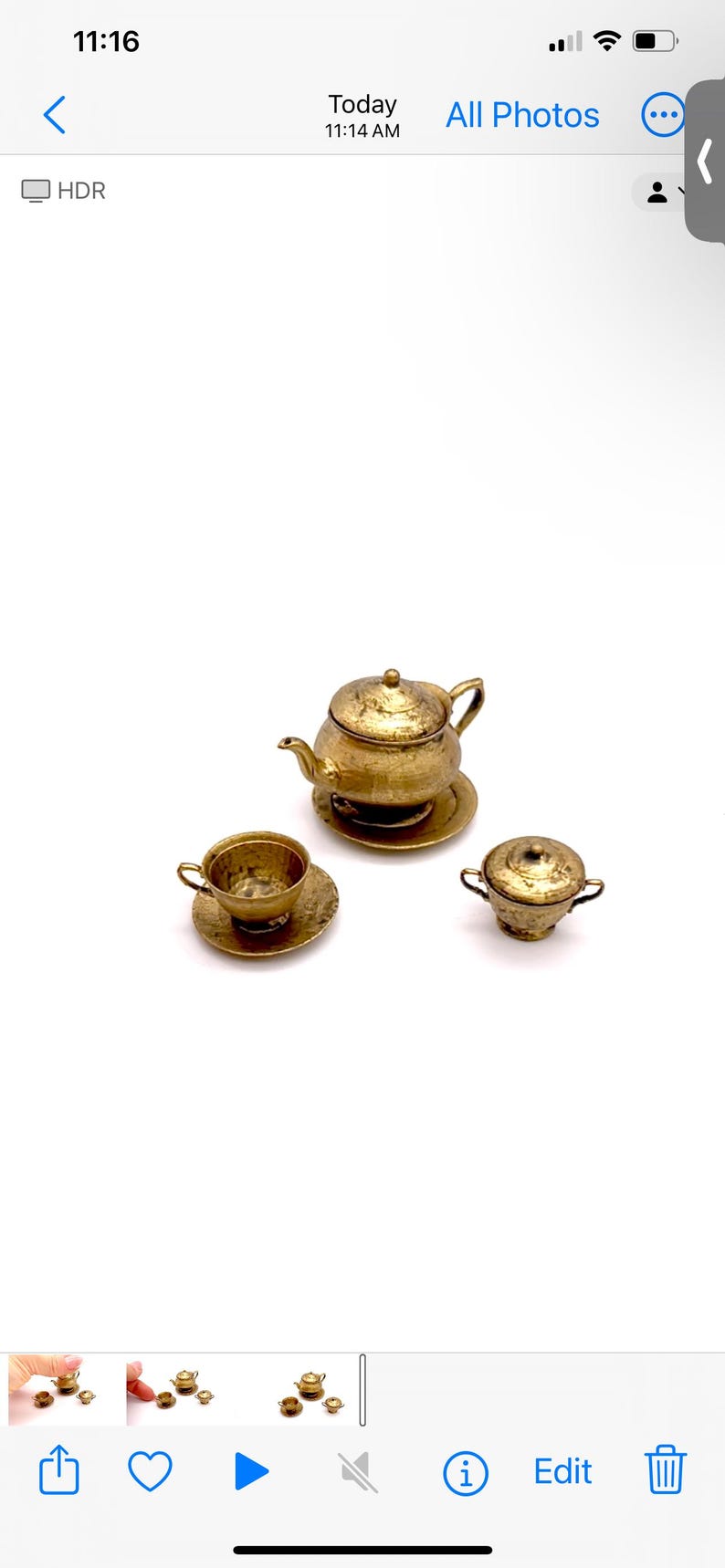 May include: A miniature gold tea set with a teapot, cup and saucer, and a creamer. The set is made of metal and has a hammered finish.