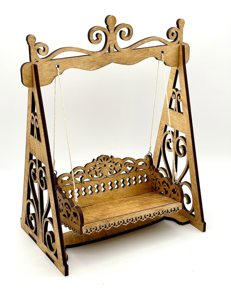 May include: A wooden swing set with intricate cutouts and a detailed design. The swing is made of wood and has a natural finish. The swing set is perfect for adding a touch of whimsy to any home.