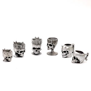 May include: Set of six silver skull shot glasses, some with crowns, some with handles.