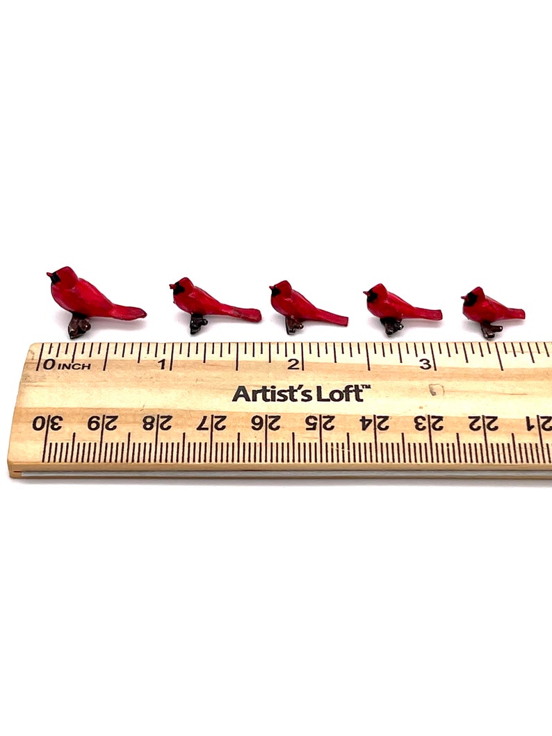 Puede incluir: Cinco figuritas de cardenal rojo en miniatura alineadas en una regla de madera. La regla est&aacute; marcada en pulgadas y tiene el texto "Artist's Loft" impreso en ella.