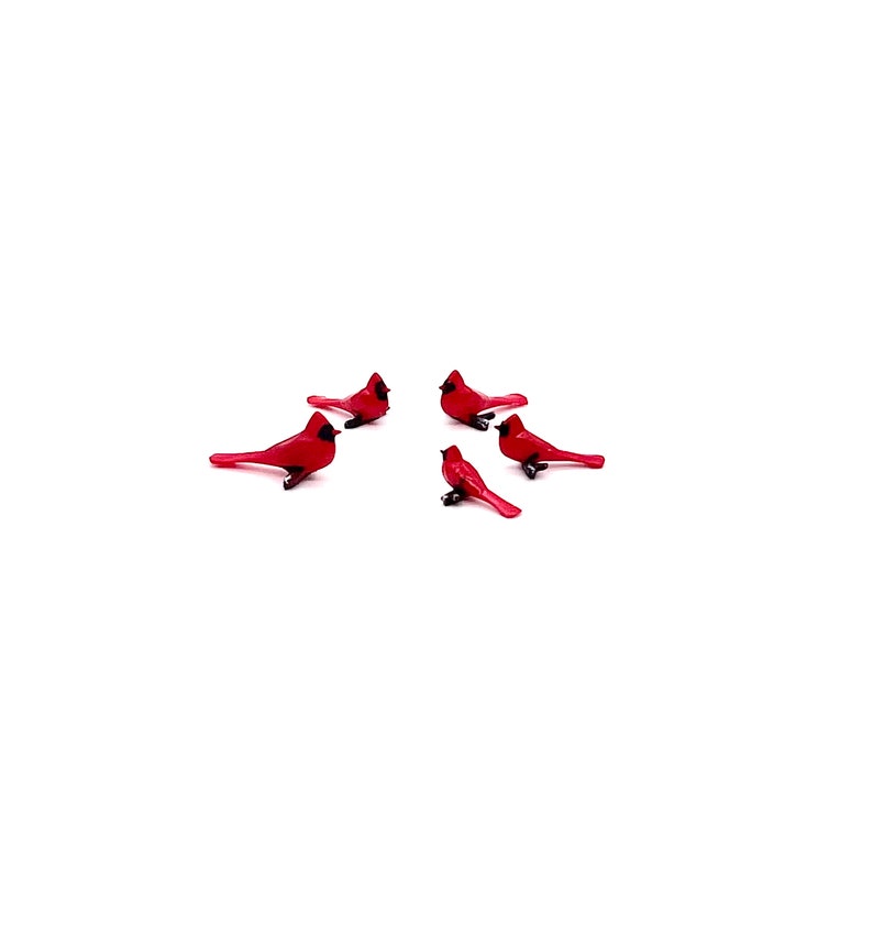 Puede incluir: Cinco figuritas de p&aacute;jaros cardenal rojo dispuestas en c&iacute;rculo sobre un fondo blanco.
