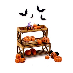 May include: A wooden stand with two shelves displays a variety of carved pumpkins. The pumpkins are orange and have different facial expressions. There are also black bats cutouts on a white background.