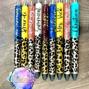 May include: Ten black and gold glitter pens with leopard print accents. Each pen has a different name written on it, including "Mrs. Vick", "Christina", and "Summeral".