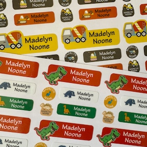 Pu&ograve; includere: Un foglio di adesivi rettangolari colorati con il nome "Madelyn Noone" stampato su ciascuno. Gli adesivi presentano varie illustrazioni, tra cui dinosauri, camion da costruzione e una variet&agrave; di colori.