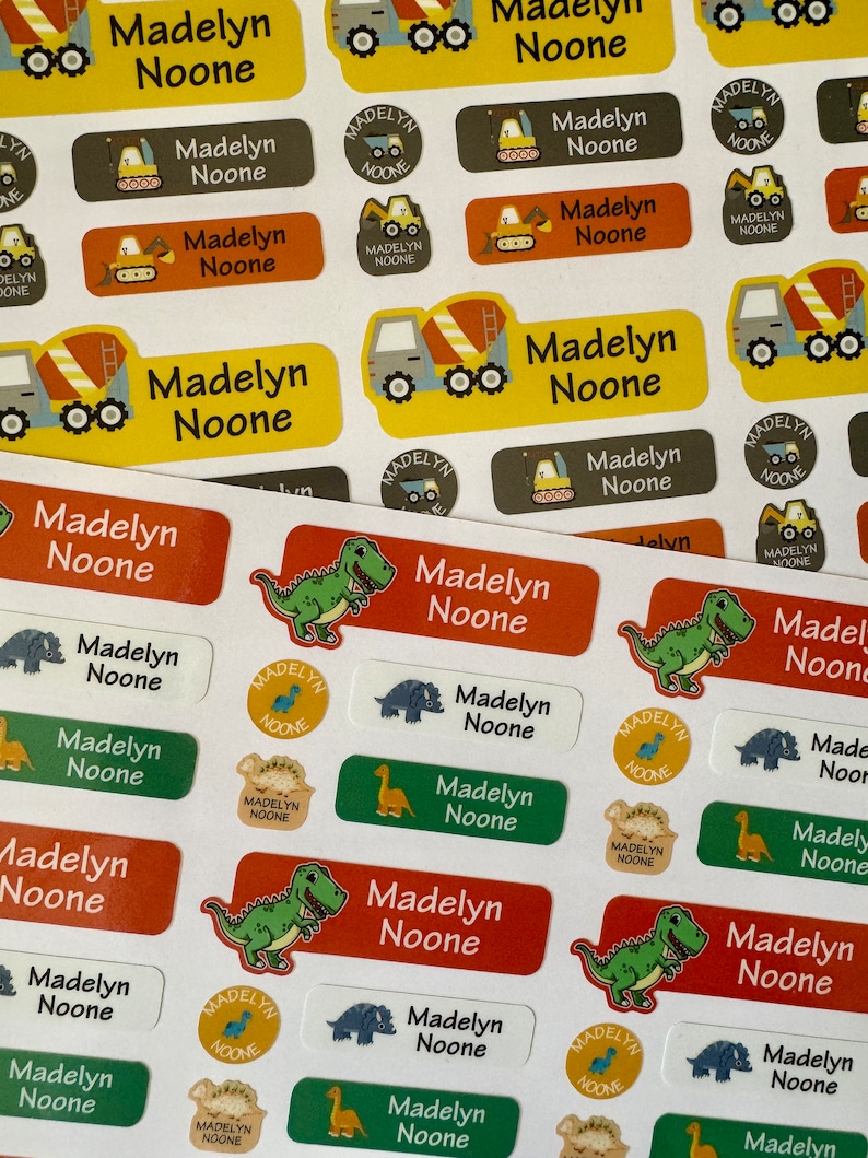 Pu&ograve; includere: Un foglio di adesivi rettangolari colorati con il nome "Madelyn Noone" stampato su ciascuno. Gli adesivi presentano varie illustrazioni, tra cui dinosauri, camion da costruzione e una variet&agrave; di colori.